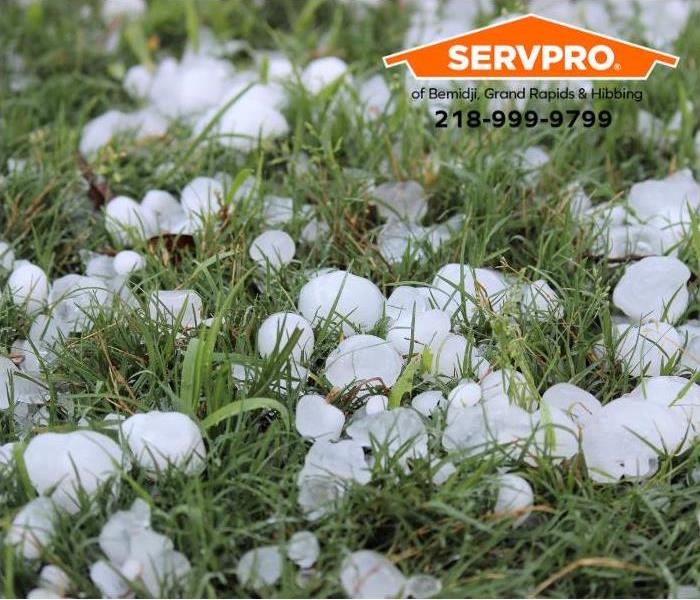 Golf ball-sized hailstones cover a lawn.