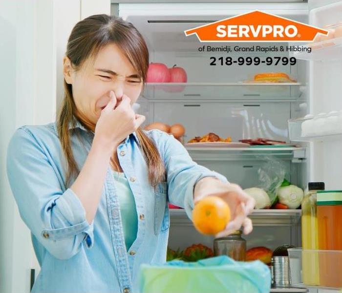 A person removes spoiled food from a refrigerator.
