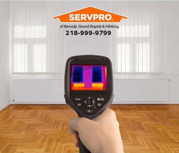 A person uses an infrared camera to detect temperature changes that may indicate hidden water damage.