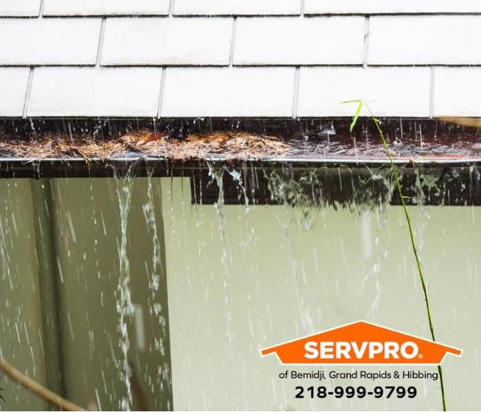 A clogged rain gutter prevents water from flowing into the downspout. 