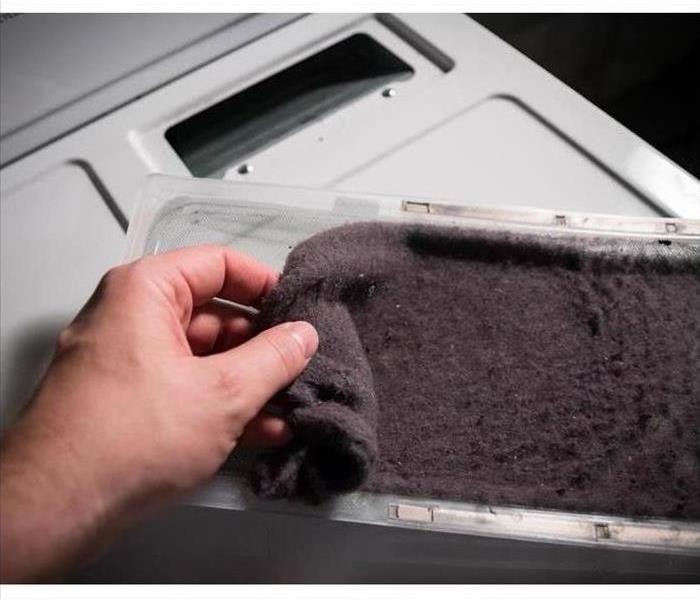 Pull the lint trap from the top or front of the dryer and remove the lint by hand.